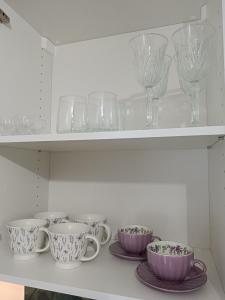 a shelf with cups and plates and wine glasses at Graphite Residence Chynowo in Chynowo