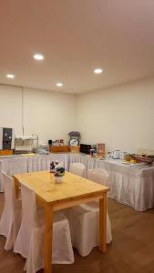 a room with a wooden table and white chairs at Sindy's Hostel in Pattaya
