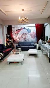 a living room with couches and tables and a painting at Sindy's Hostel in Pattaya