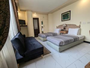 a hotel room with two beds and a couch at New Panoramic Hotel in Lahore