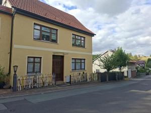 a yellow house with a fence on a street at Horstis Fewo Apartment Reni in Frankenhain