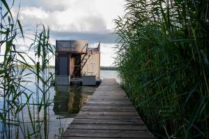 a small house on a dock in the water at Houseboat Dąbrowica in Dąbrowica