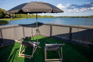 two chairs and an umbrella on the deck of a boat at Houseboat Dąbrowica in Dąbrowica
