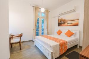 a bedroom with a bed and a chair and a window at Glowing Crescent Holiday Apartments in Rajagiriya
