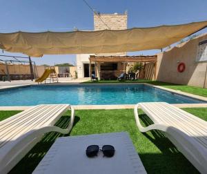 a pair of sunglasses sitting on a bench next to a swimming pool at Entire Home Near Deadsea & Baptism Site Pool, Garden, BBQ, Great Price in Shūnat Nimrīn
