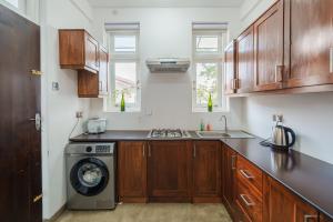 a kitchen with wooden cabinets and a washing machine at Glowing Crescent Holiday Apartments in Rajagiriya