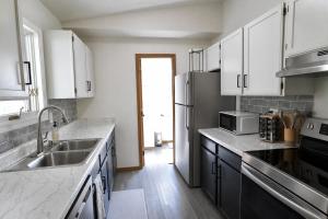 a kitchen with white cabinets and a stainless steel refrigerator at Pet-Family-Friendly Duplex with Parking in Wasilla