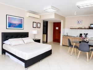 a bedroom with a large bed and a kitchen at Apartamentos - Torre de Cali in Cali
