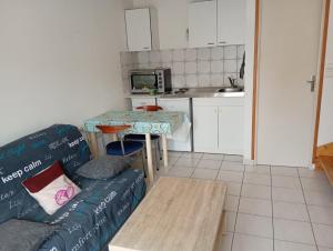 a living room with a couch and a table and a kitchen at La maison aux papillons in Tregueux