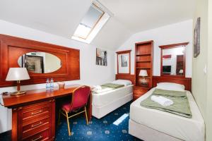 a room with two beds and a desk with a desk at Vila Sentandreja in Subotica