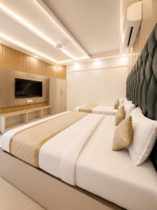a bedroom with a large white bed with a tv on the wall at Hotel Satwah Luxe Stay - 1 Minute From Nizamuddin Railway Station And India Gate in New Delhi