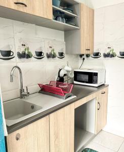 a kitchen with a sink and a microwave on a counter at L'échappée verte in Chirongui