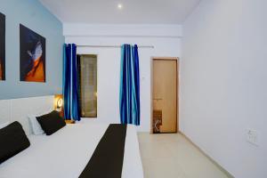 a bedroom with a bed with blue curtains and a door at Hotel O City Star in Rewa