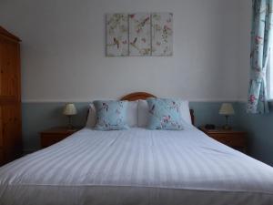 a bedroom with a bed with blue and white sheets at The Denewood in Sandown