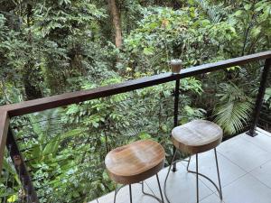 two stools sitting on a balcony in the jungle at Private Rainforest Cottage - Bingil Bay in Mission Beach