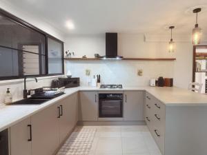 a kitchen with white cabinets and a sink and a stove at Private Rainforest Cottage - Bingil Bay in Mission Beach