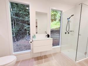 a bathroom with a toilet and a sink and a shower at Private Rainforest Cottage - Bingil Bay in Mission Beach +16 photos