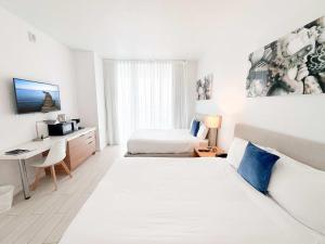 a hotel room with two beds and a desk at 30th Fl Beachwalk Studio Bay Balcony in Hallandale Beach