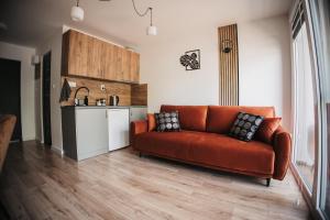 a living room with an orange couch and a kitchen at Apart & Plus 1 in Okuninka