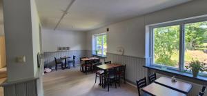 a dining room with tables and chairs and windows at Frostavallen Hostel in Långstorp