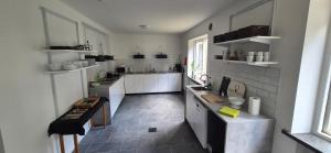 a large kitchen with white cabinets and a tile floor at Frostavallen Hostel in Långstorp