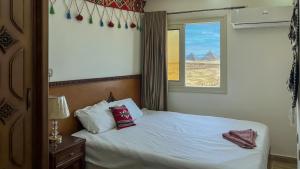 a bedroom with a bed with two pillows and a window at Atlantis Pyramids Inn in Giza