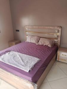 a bed with purple sheets and pillows in a bedroom at The blue door meknes in Meknès