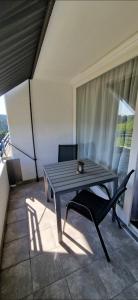 a wooden table and a chair on a balcony at Ferienwohnung Ronja im Hause Bergland Altreichenau in Neureichenau