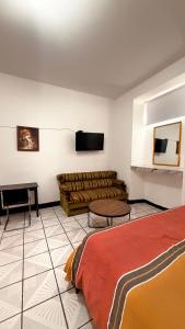 Hotel Dulce Morelia في موريليا: غرفة معيشة بها أريكة وجهاز تلفزيون