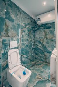 a bathroom with a toilet in a blue tiled wall at Kotarja Apartments in Dhërmi +153 photos