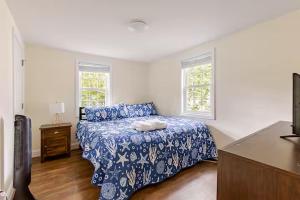 a bedroom with a bed with a blue bedspread and two windows at Dennis Beach House - Walk to Beach - Pet Friendly in Dennis