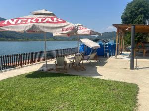 two chairs and an umbrella next to a body of water at Lure House in Mali Zvornik