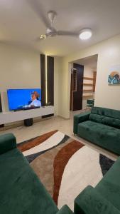 a living room with two green couches and a flat screen tv at Gods Grace homes in Duasi