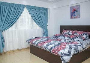 a bedroom with a bed with blue curtains and a window at Gods Grace homes in Duasi