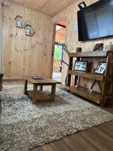 a living room with a table and a flat screen tv at Casa Salto Pichi Ignao in Lago Ranco +23 photos