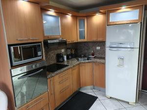 a kitchen with wooden cabinets and a white refrigerator at Apto RE 1 in El Morro de Barcelona