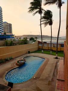 a swimming pool with a boat in it with palm trees at Apto RE 1 in El Morro de Barcelona
