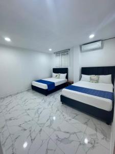 two beds in a room with marble floors at Mi Casa18 in Santa Marta