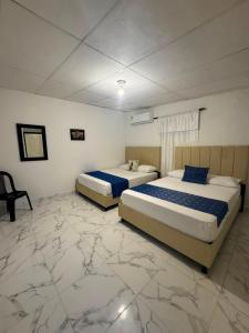 two beds in a room with marble floors at Mi Casa18 in Santa Marta