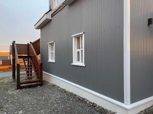 a gray building with two windows and a staircase at Bjarg at Lyngholt in Þórshöfn +5 photos
