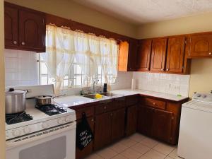 a kitchen with wooden cabinets and a stove top oven at Guest house 2 in Upper Conaree