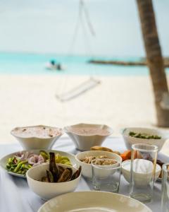 a table with bowls and plates of food on it at Naeco Select Pearl in Hanimaadhoo