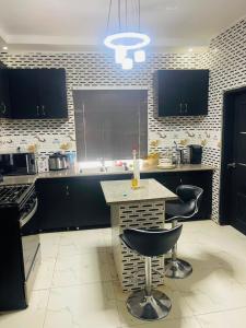 a kitchen with black cabinets and a table and chairs at Sowe's Villa in Old Yundum