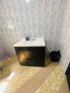 a bathroom with a sink and a white tiled wall at Sowe's Villa in Old Yundum +15 photos