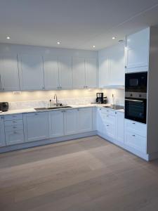 a large white kitchen with white cabinets and appliances at Fjallbacka, Modern nyproducerad lägenhet med egen parkering och laddning in Fjällbacka