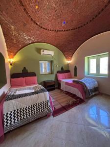 two beds in a room with a brick ceiling at فيلا كوكو بقرية تونس in Tunis