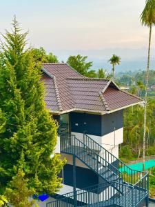 a house with a large deck next to a tree at Mount Ocio Pool Resort Wayanad, Chulliyode in Ambalavayal