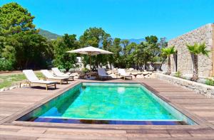 a pool with chairs and an umbrella on a patio at Villa Rosa, 4chambres, piscine , Lecci , 8 personnes in Lecci