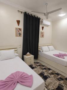 two beds in a room with purple bows on them at Garden view in Aswan