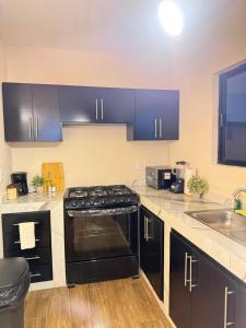 a kitchen with black cabinets and a stove top oven at Casa Cielo del Mar in Ciudad Madero